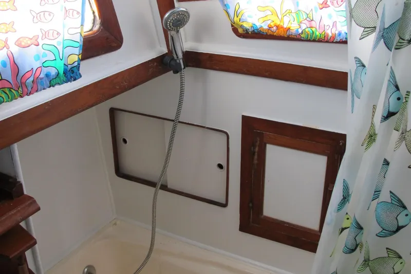 Slide: The Image of 1981 Albin 36 boat bathroom with colorful fish-themed curtains and wooden accents. - 29