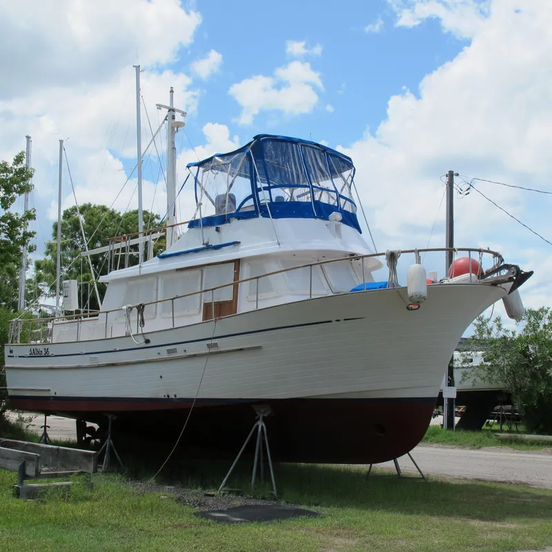 Slide: The Image of 1981 Albin 36 boat on land with blue canopy under a cloudy sky. - 3