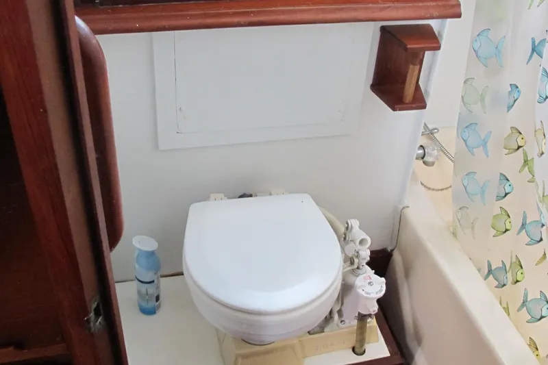Slide: The Image of 1981 Albin 36 boat bathroom with toilet, fish-themed shower curtain, and wooden accents. - 31