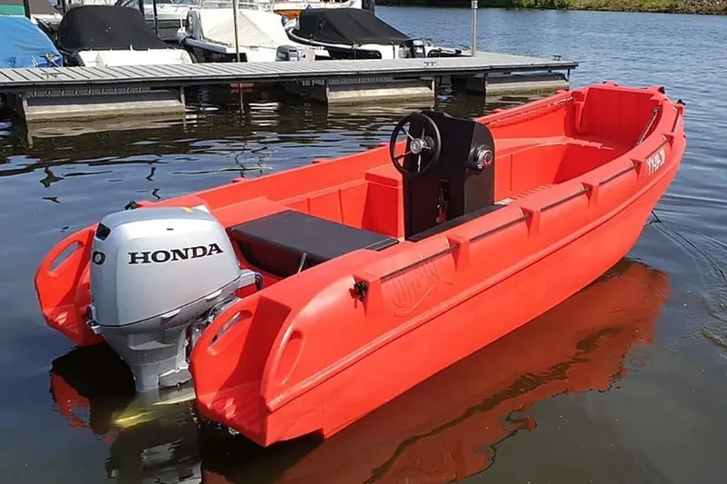 Slide: The Image of Red 2023 Whaly 455 R boat with Honda outboard motor docked on calm water. - 1