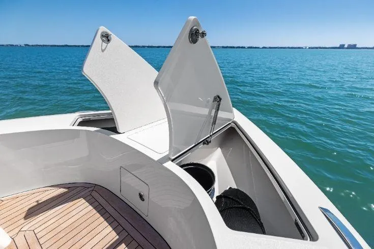 Slide: The Image of 2026 Scout 670 LXS boat with open storage compartments on a sunny day at sea. - 10