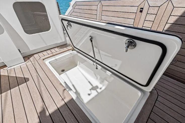 Slide: The Image of 2026 Scout 670 LXS boat storage compartment with open lid on teak deck. - 21