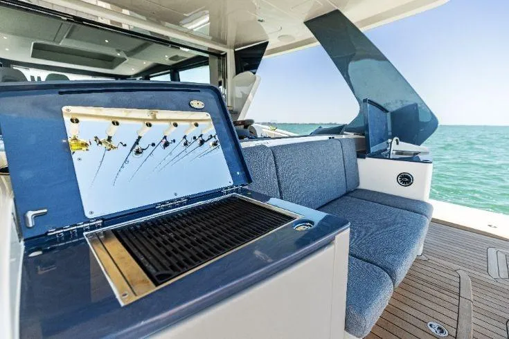 Slide: The Image of 2026 Scout 670 LXS boat interior with grill and blue seating, ocean view. - 24