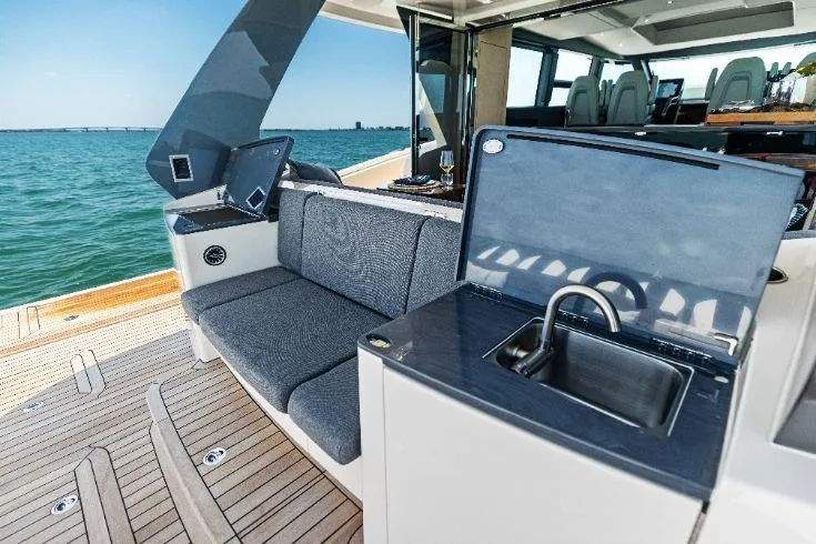 Slide: The Image of Luxurious 2026 Scout 670 LXS yacht interior with seating and kitchenette, overlooking the ocean. - 26