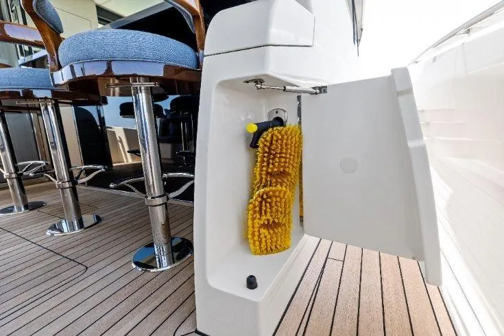 Slide: The Image of 2026 Scout 670 LXS boat with open storage compartment and cleaning brushes on deck. - 32