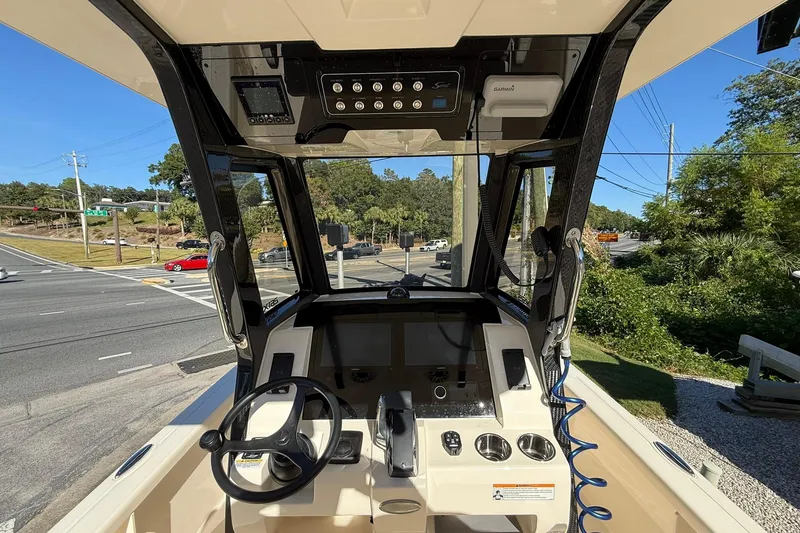 Slide: The Image of 2026 Scout 261 XSS boat dashboard with steering wheel and control panel, parked near a road. - 15