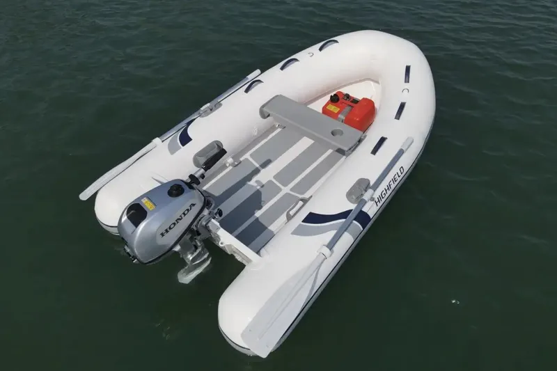 Slide: The Image of 2025 Highfield UltraLite 290SS inflatable boat with Honda outboard motor on water. - 2