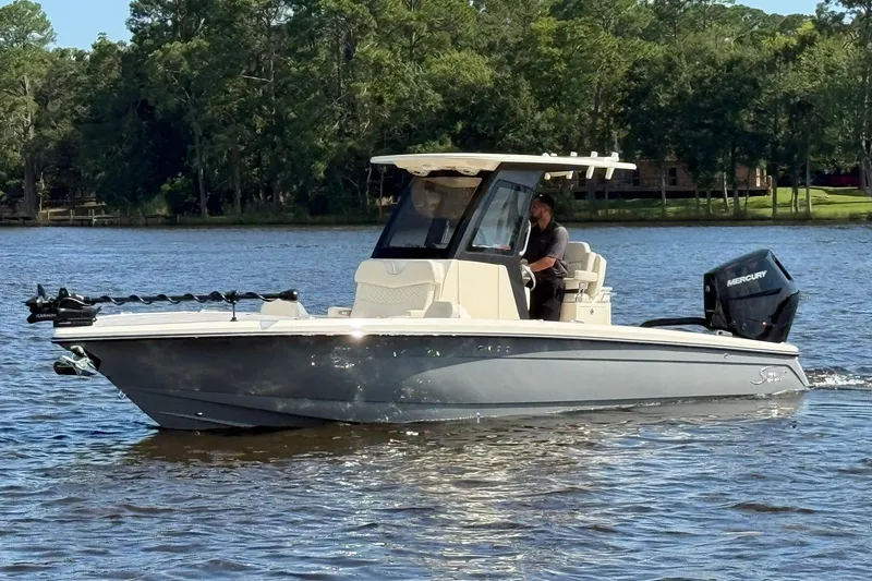 Slide: The Image of 2026 Scout 281 XSS boat cruising on a serene lake with lush green trees. - 2