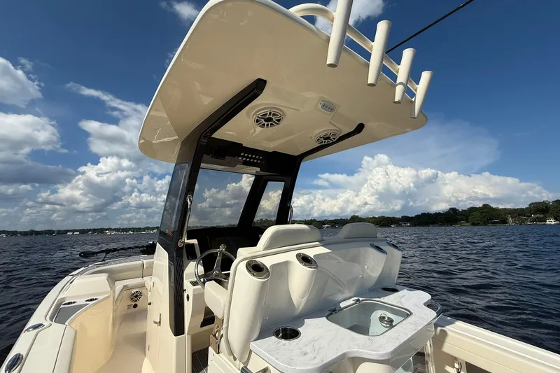 Slide: The Image of 2026 Scout 281 XSS boat interior with helm, rod holders, and seating on a sunny day. - 21