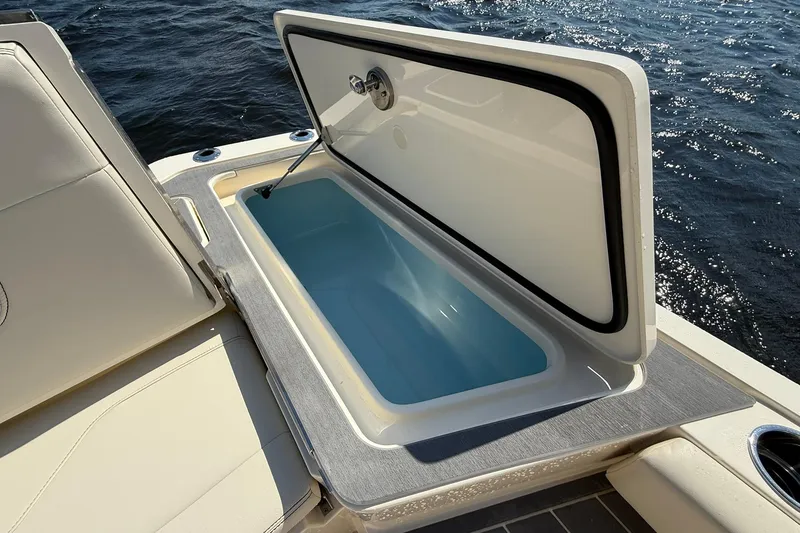 Slide: The Image of Open storage compartment on 2026 Scout 281 XSS boat, near water. - 27