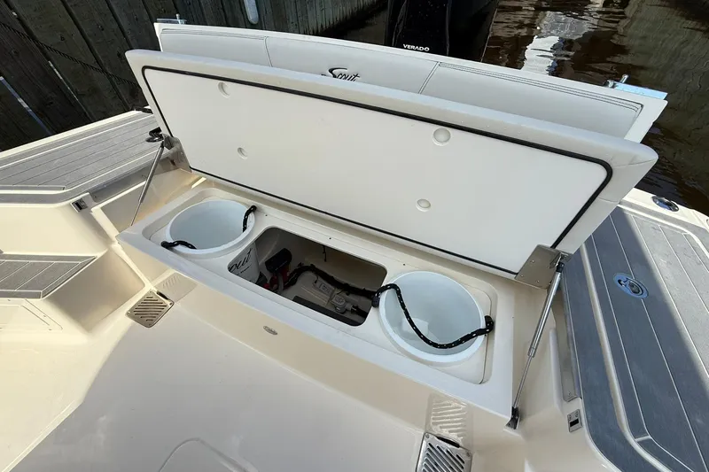 Slide: The Image of Open storage compartment on 2026 Scout 281 XSS boat, featuring buckets and equipment. - 30