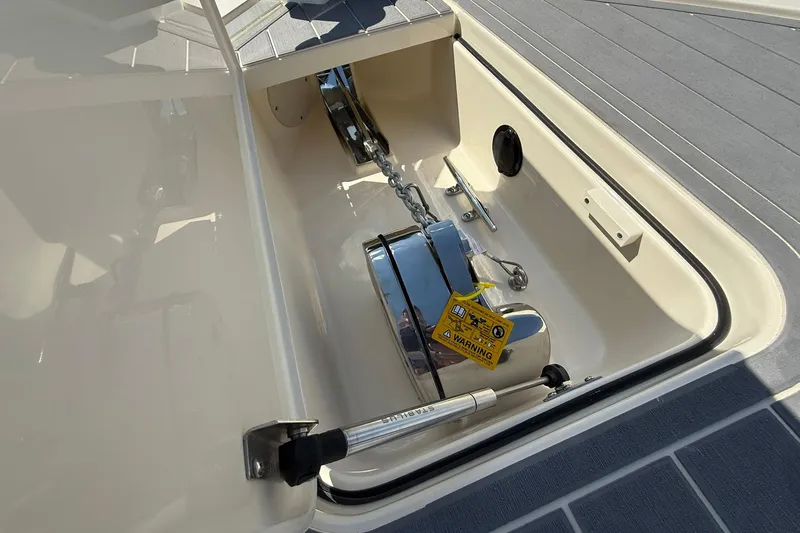 Slide: The Image of Anchor compartment of 2026 Scout 281 XSS boat, featuring a secured chain and warning label. - 6
