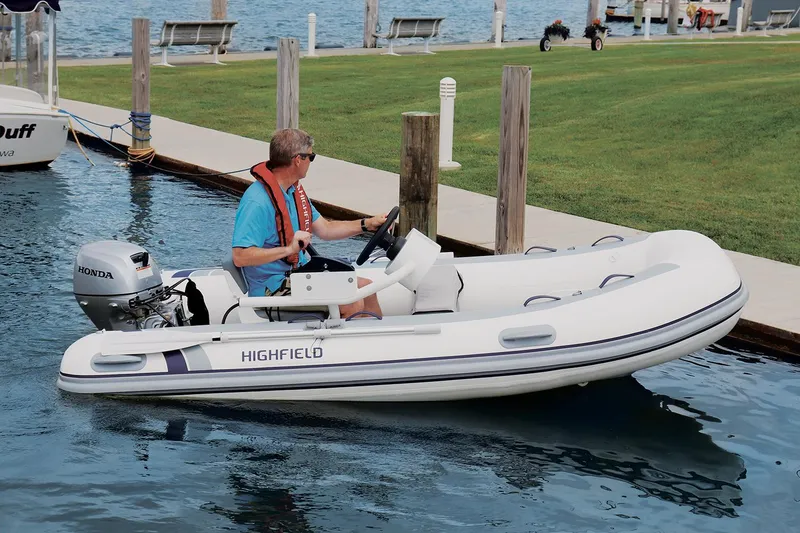 The Image of Man piloting 2024 Highfield Classic 310 FCT boat on calm water near dock. - 0