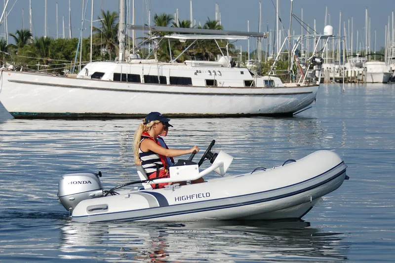 Slide: The Image of 2024 Highfield Classic 310 FCT boat on calm water, with a Honda outboard motor. - 2