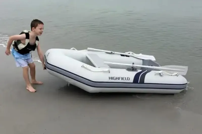 Slide: The Image of Boy pulling 2025 Highfield Roll-Up 320 KAL inflatable boat on sandy beach. - 2