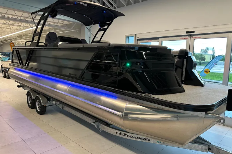 Slide: The Image of 2025 Veranda VX 27 DCRC pontoon boat with sleek black design and blue LED lighting. - 0