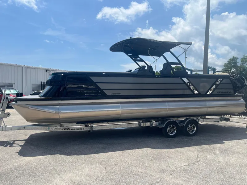 Slide: The Image of 2025 Veranda VX 27 DCRC pontoon boat on trailer under clear sky. - 1