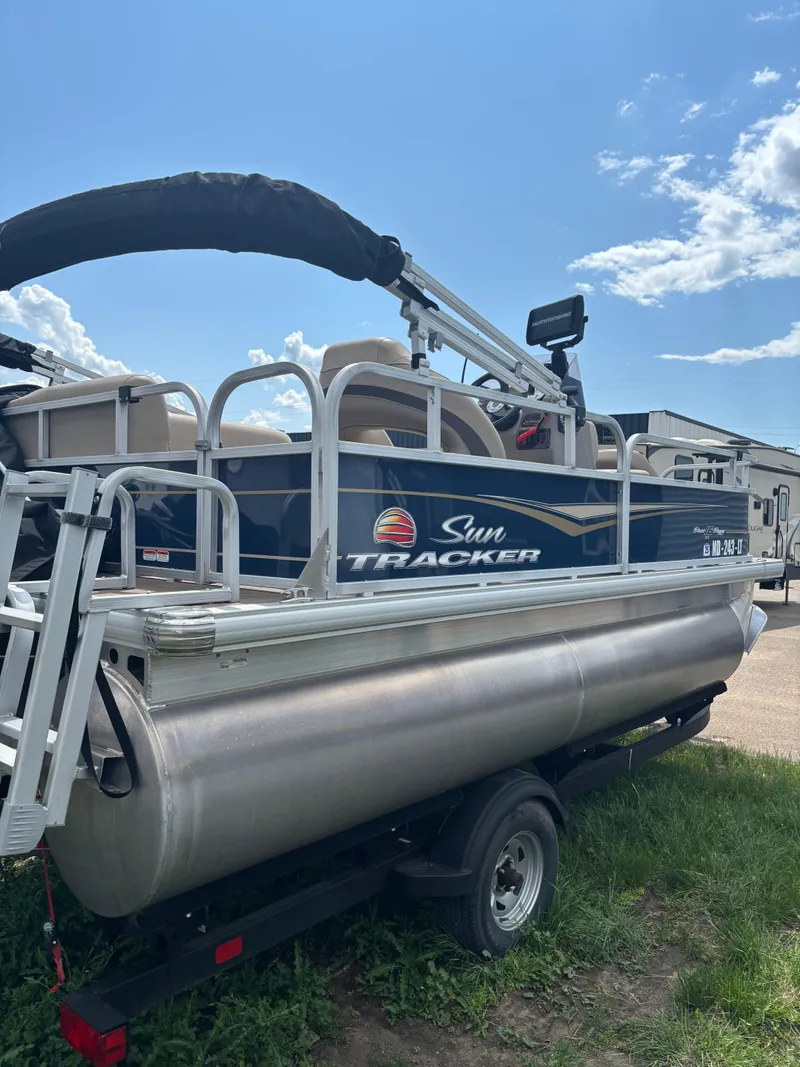 Slide: The Image of 2022 Sun Tracker Bass Buggy 16 XL Select pontoon boat on trailer, under blue sky. - 2