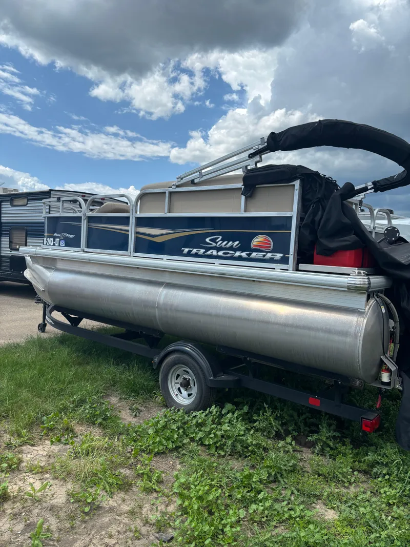 Slide: The Image of 2022 Sun Tracker Bass Buggy 16 XL Select pontoon boat on trailer under cloudy sky. - 3
