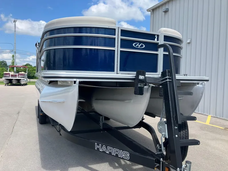 Slide: The Image of 2023 Harris Cruiser 230 pontoon boat on trailer, parked outdoors under blue sky. - 14