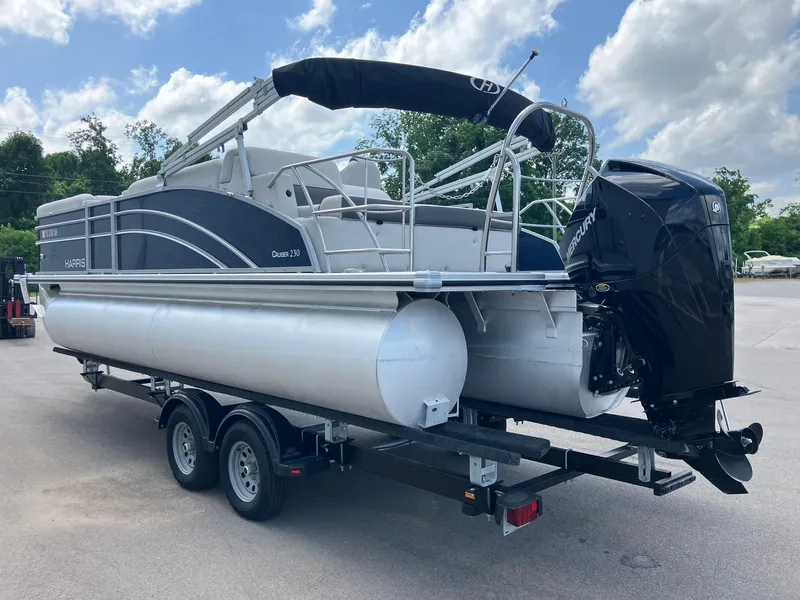 Slide: The Image of 2023 Harris Cruiser 230 pontoon boat on trailer, parked outdoors under a cloudy sky. - 4