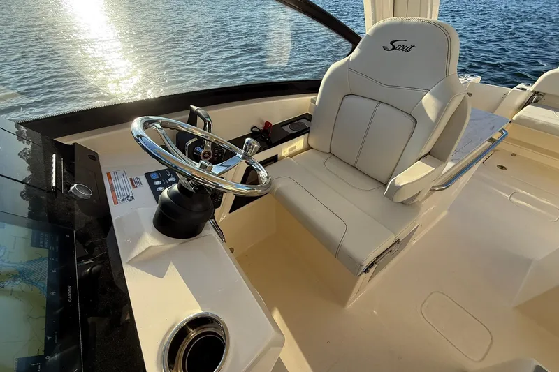 Slide: The Image of 2026 Scout 277 Dorado boat helm with luxurious seating and steering wheel, overlooking water. - 15