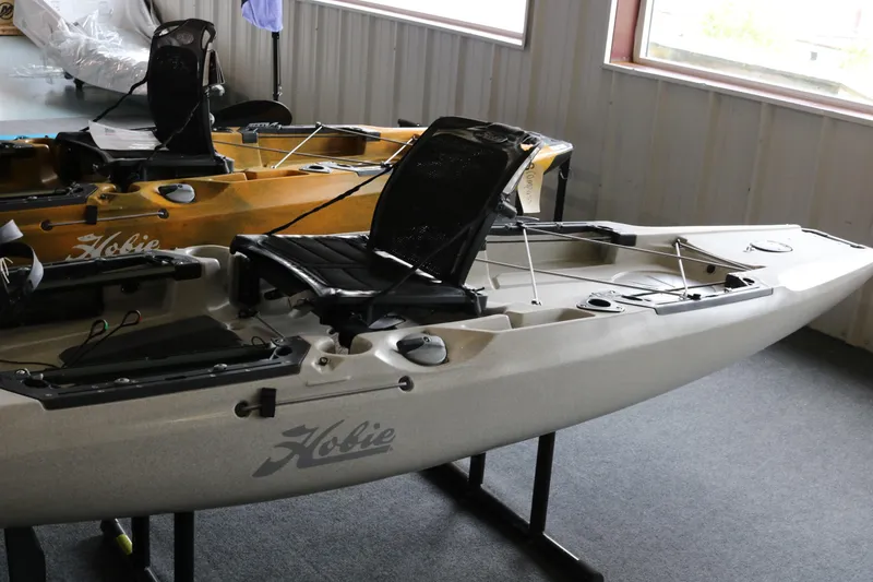 The Image of 2023 Hobie Mirage Outback kayak displayed indoors on a stand. - 0