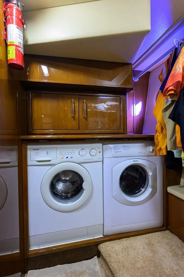 Slide: The Image of Laundry area inside a 2005 Marquis 65 MY yacht, featuring a washer and dryer. - 30