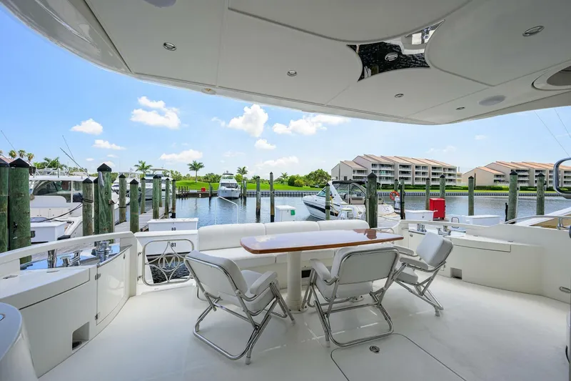 Slide: The Image of Luxurious 2005 Marquis 65 MY yacht deck with seating, docked at a marina under a clear blue sky. - 31