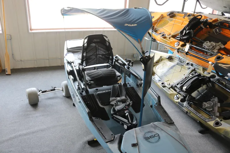 Slide: The Image of 2023 Hobie Mirage Pro Angler 14 kayak with canopy and wheels in showroom. - 3