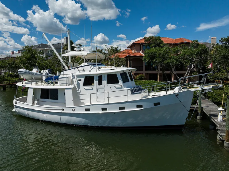 The Image of 2013 Krogen 44' AE Widebody yacht docked by waterfront homes under blue sky. - 0