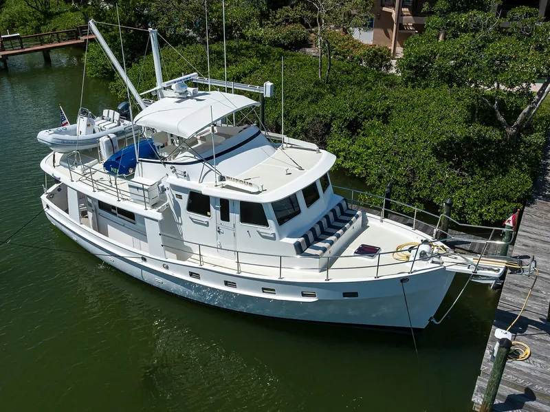 Slide: The Image of 2013 Krogen 44' AE Widebody yacht docked in a serene, lush marina setting. - 32