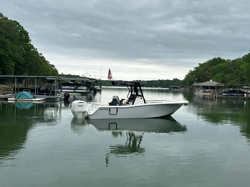 Slide: The Image of 2025 Tidewater 256 LXF boat docked on a calm lake under cloudy skies. - 0