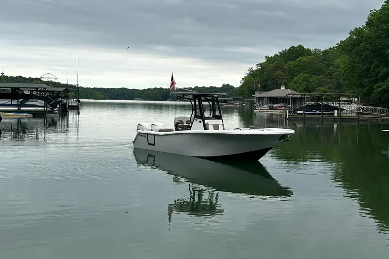 Slide: The Image of 2025 Tidewater 256 LXF boat on a calm lake with docks and trees. - 11