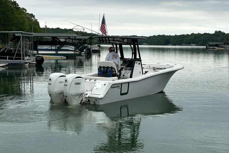 Slide: The Image of 2025 Tidewater 256 LXF boat with dual Yamaha engines on a calm lake. - 12