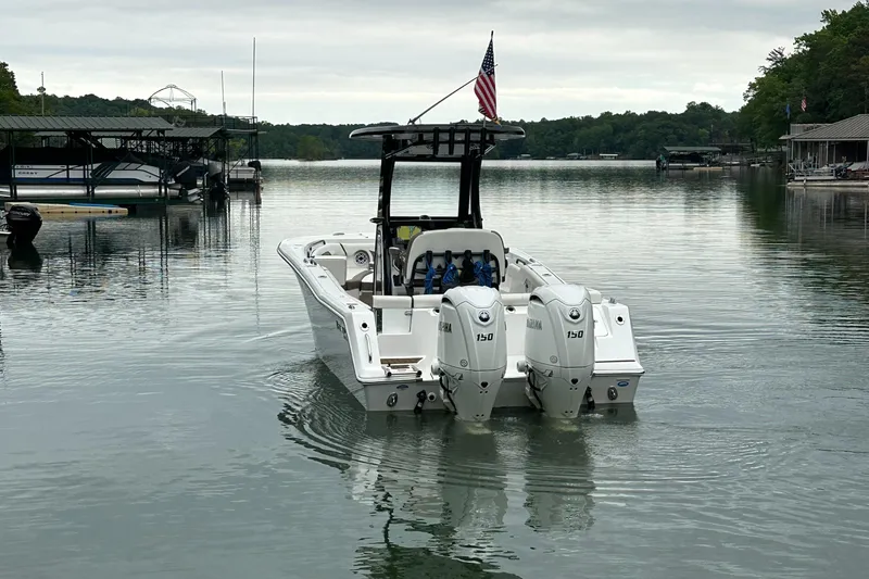 Slide: The Image of 2025 Tidewater 256 LXF boat with dual Yamaha engines on a calm lake. - 14