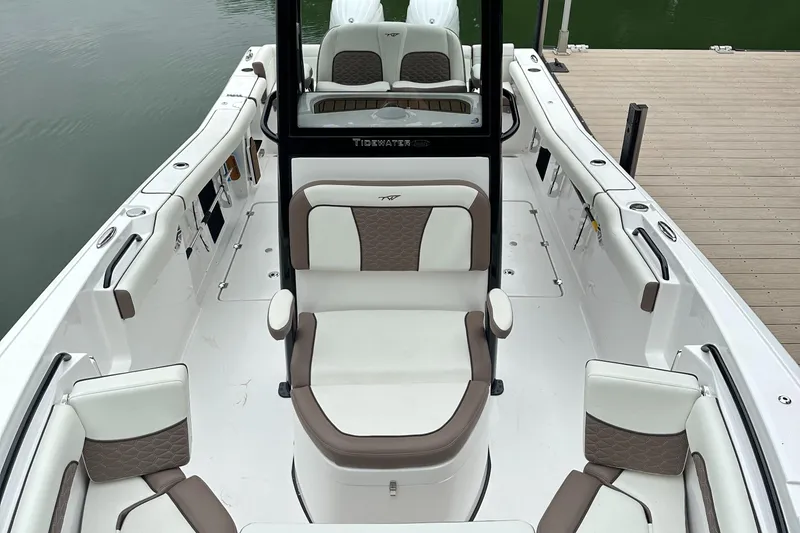Slide: The Image of 2025 Tidewater 256 LXF boat interior with white and brown seating, docked by water. - 15