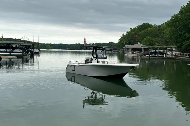 Slide: The Image of 2025 Tidewater 256 LXF boat on calm lake with docks and trees in background. - 4