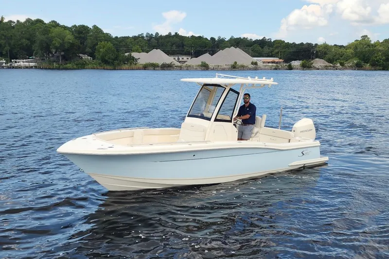 Slide: The Image of 2026 Scout 240 XSF boat on a calm lake with a person at the helm. - 0