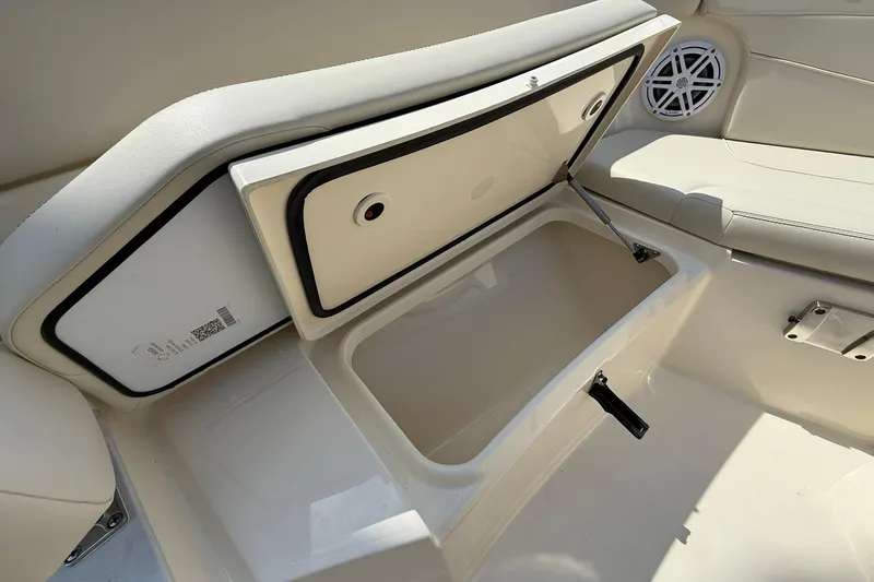 Slide: The Image of 2026 Scout 240 XSF boat interior storage compartment with cushioned seating and speaker. - 12