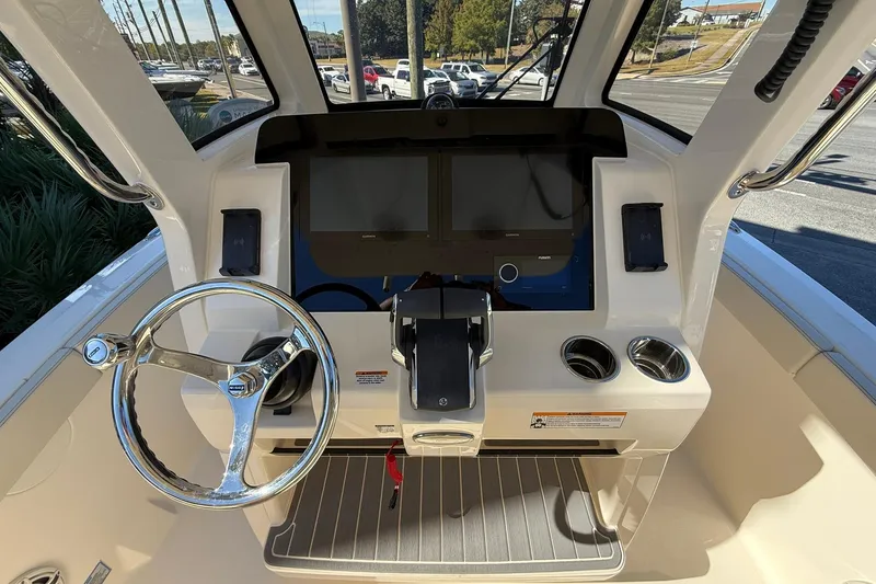Slide: The Image of 2026 Scout 260 LXF boat helm with steering wheel, touchscreen display, and control panel. - 18