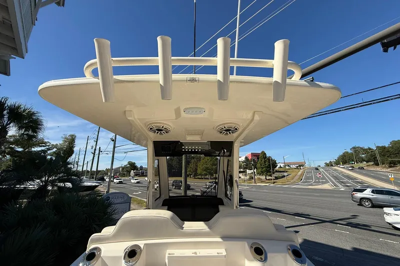 Slide: The Image of 2026 Scout 260 LXF boat with T-top and rod holders, parked near a road. - 20