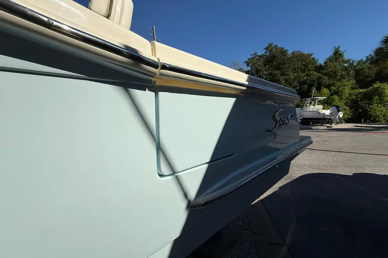 Slide: The Image of 2026 Scout 260 LXF boat side view with logo, parked outdoors under clear sky. - 25