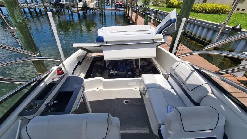 Slide: The Image of 2018 Formula 270 Bowrider boat interior with open engine compartment, docked by water. - 17