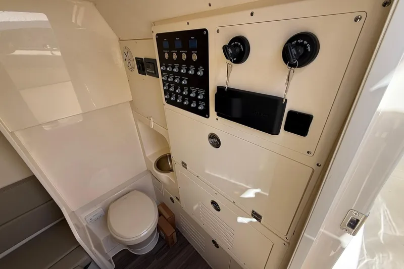 Slide: The Image of Interior of 2026 Scout 330 LXF boat featuring control panel and compact bathroom. - 16
