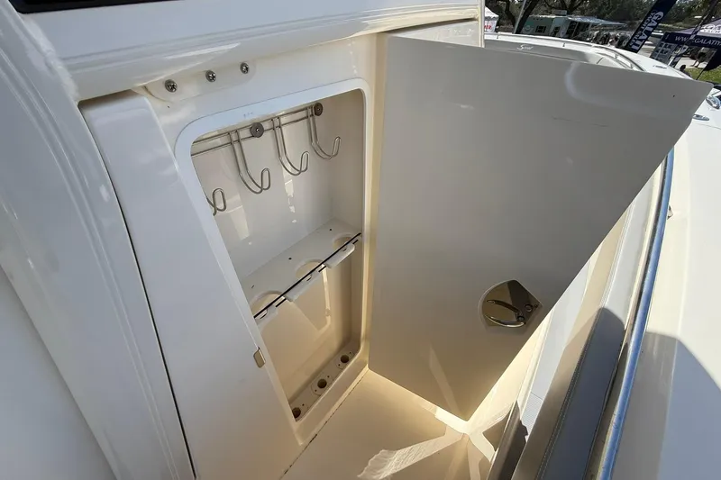 Slide: The Image of 2026 Scout 330 LXF boat storage compartment with hooks and open door. - 18