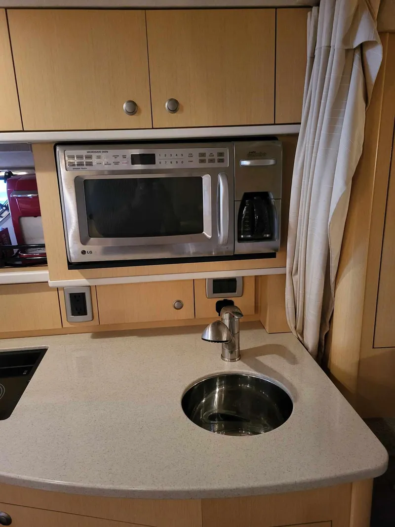 Slide: The Image of 2009 Sea Ray 310 Sundancer galley with microwave, sink, and cabinetry. - 16