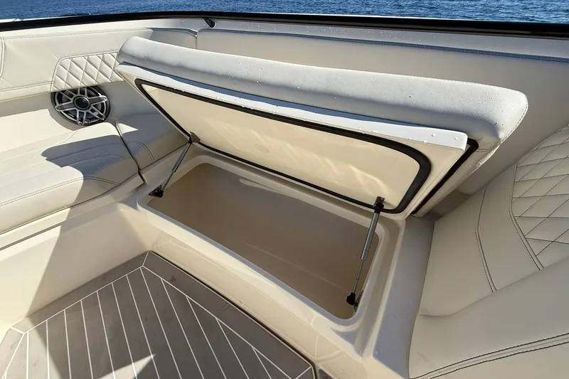 Slide: The Image of 2026 Scout 357 LXF boat interior storage compartment with cushioned seating and speaker. - 10