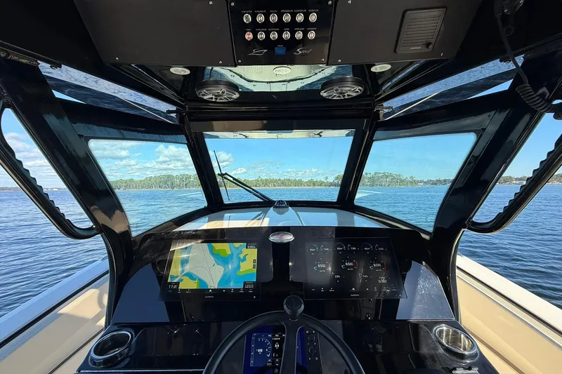 Slide: The Image of Cockpit view of 2026 Scout 357 LXF boat with navigation screens on open water. - 27