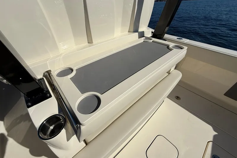 Slide: The Image of 2026 Scout 357 LXF boat interior with foldable table and cup holders, overlooking the ocean. - 31